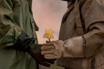 A man and a woman in a chemical protection suit. A man gives a flower to his woman....