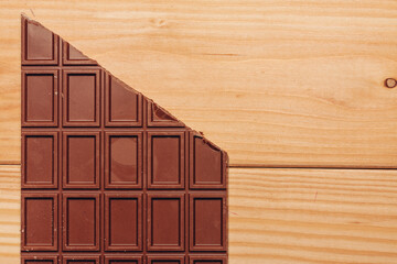 brown chocolate bar cut diagonally on wooden background