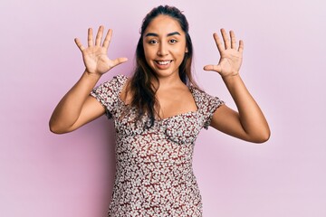 Young latin woman wearing casual clothes showing and pointing up with fingers number ten while smiling confident and happy.