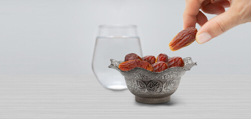 Typical of the month of Ramadan for muslims is the setting here, after the fast has been broken - water and pitted dates. Traditional iftar food.
metal bowl full of date fruits symbolizing Ramadan - obrazy, fototapety, plakaty