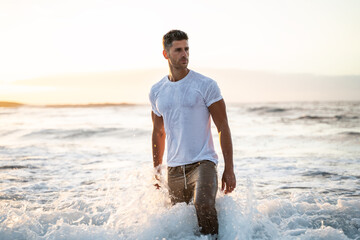 Attractive muscular young athletic man standing in the ocean.