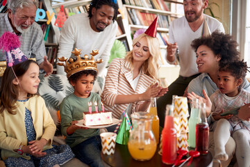 Family and friends singing a birthday song to a little celebrant at his birthday party at home. Family, celebration, together