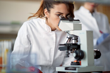 A young female student using a microscope in a laboratory. Science, chemistry, lab, people