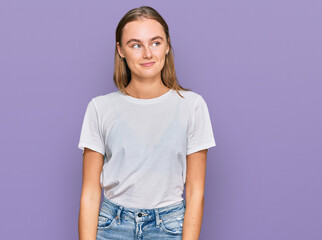 Beautiful young blonde woman wearing casual white t shirt smiling looking to the side and staring away thinking.