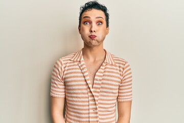 Obraz premium Handsome man wearing make up wearing casual t shirt puffing cheeks with funny face. mouth inflated with air, crazy expression.