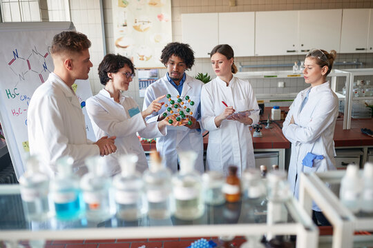 Young chemical students learning on molecule model in the university laboratory. Science, chemistry, lab, people