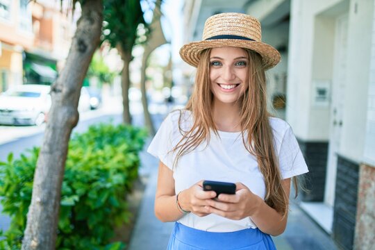 Young blonde woman on vacation smiling happy using smartphone at street of city