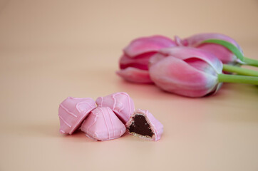 Fototapeta na wymiar Pink chocolate candies and tulips