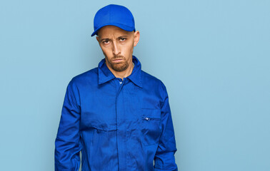 Bald man with beard wearing builder jumpsuit uniform skeptic and nervous, frowning upset because of problem. negative person.