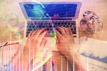 Double exposure of man's hands typing over laptop keyboard and forex chart hologram drawing. Top view. Financial markets concept.