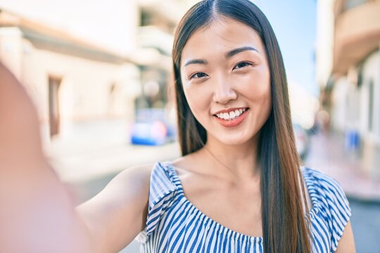Young chinese woman smiling happy making selfie by the camera at street of city.