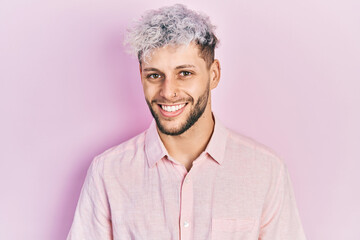 Young hispanic man with modern dyed hair wearing casual pink shirt with a happy and cool smile on face. lucky person.