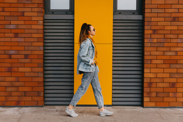 Young woman wearing denim clothes, walking on city street.