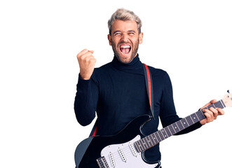 Young handsome blond man playing electric guitar screaming proud, celebrating victory and success very excited with raised arms