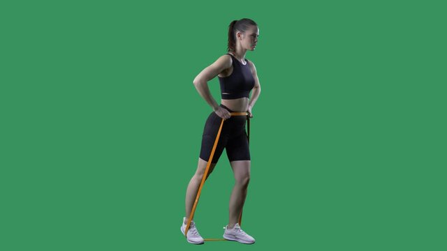 Side view of fit woman doing legs kickback exercises with resistance band. Full body on green screen chroma background. 