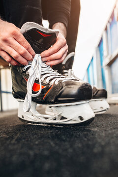 A hockey player on a bench behind the side straightens his skates before the match