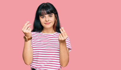 Young hispanic girl wearing casual clothes doing money gesture with hands, asking for salary payment, millionaire business