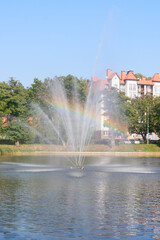 Fountain on lake with rainbow in splashes of water. Selective focus, blur