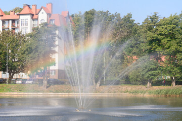 Fountain with rainbow in sunlight. Selective focus, blur