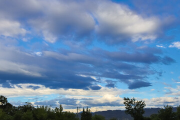 Blue sky approaching dusk, big thick clouds, and mountains.