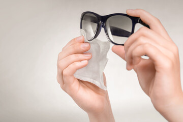 women's hands wipe their sunglasses with a napkin