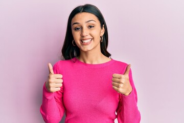 Young hispanic woman wearing casual clothes success sign doing positive gesture with hand, thumbs up smiling and happy. cheerful expression and winner gesture.