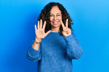 Middle age hispanic woman wearing casual clothes showing and pointing up with fingers number seven...