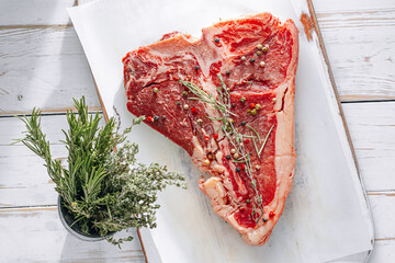 fresh and raw t-bone steak on white wooden background