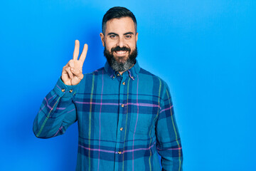 Fototapeta premium Young hispanic man wearing casual clothes showing and pointing up with fingers number two while smiling confident and happy.