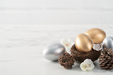 Fototapeta na wymiar Close up of golden and silver Easter eggs in the nest with white plum flower.