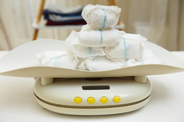 Weighing dirty used baby diapers on a scale. Determination of urine weight in one day. Medical...