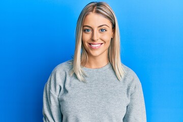 Beautiful blonde woman wearing casual clothes with a happy and cool smile on face. lucky person.