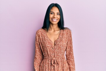 Young african american woman wearing summer dress looking positive and happy standing and smiling with a confident smile showing teeth