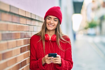 Young hispanic woman using smartphone and headphones at the city.
