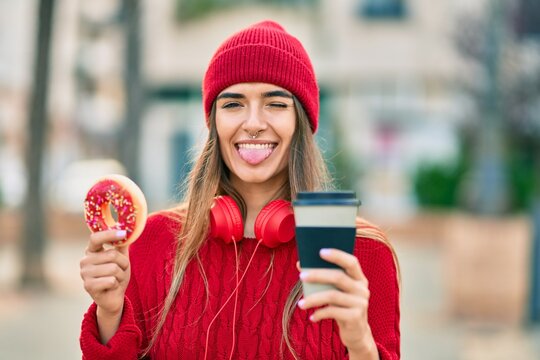 Young hispanic woman having breakfast using headphones at the city.