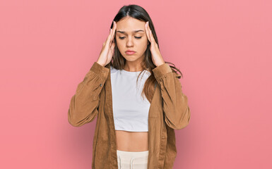 Young brunette woman wearing casual clothes suffering from headache desperate and stressed because pain and migraine. hands on head.