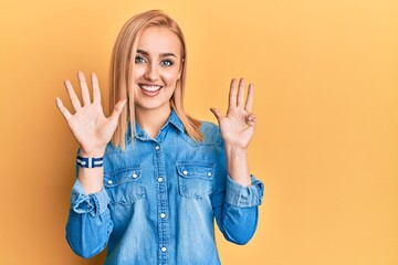 Beautiful caucasian woman wearing casual denim jacket showing and pointing up with fingers number...