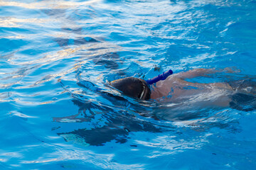 Obraz premium Boy swims in the pool in a mask and snorkel in the summer