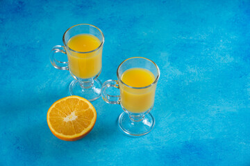 Two glass cups of juice with slice of orange
