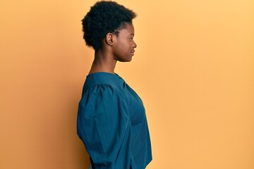 Young african american girl wearing casual clothes looking to side, relax profile pose with natural face with confident smile.
