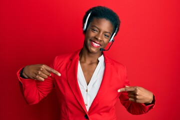 Young african american girl wearing call center agent headset looking confident with smile on face,...