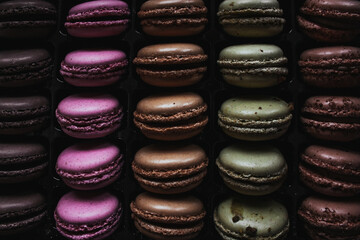 even rows of colorful bright macarons cookies in full screen for a dark background. assorted with...