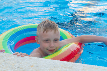 Caucasian boy swims in the summer pool on an inflatable circle
