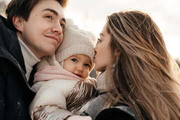 Young parernts holding small daughter in winter forest