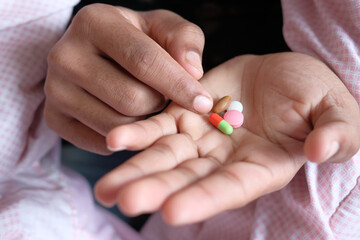 man hand with medicine spilled out of the pill container 