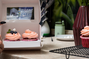 The confectioner decorates with a delicately pink cream of cupcakes in pink moulds.