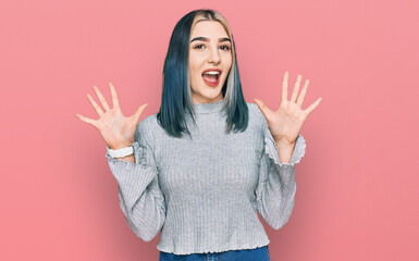 Young modern girl wearing casual sweater showing and pointing up with fingers number ten while smiling confident and happy.