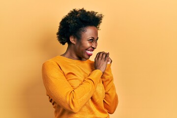 Young african american woman wearing casual clothes laughing nervous and excited with hands on chin...