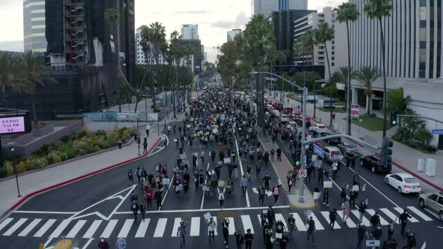 Aerial: Protestors With Placards On City Street Amidst Buildings