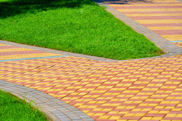 walkway made of paving slabs and green grass as a background, bright sunlight